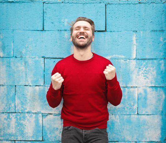 man smiling while raising clenched fists in triumph