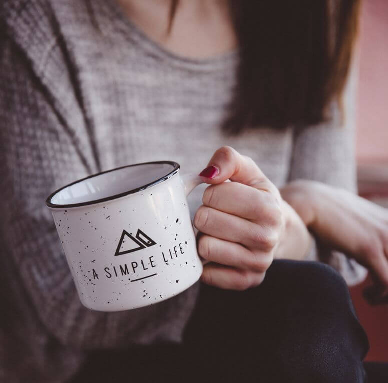 Simple living can be as simple as taking time to enjoy a refreshing cup of coffee like this woman holding a coffee cup
